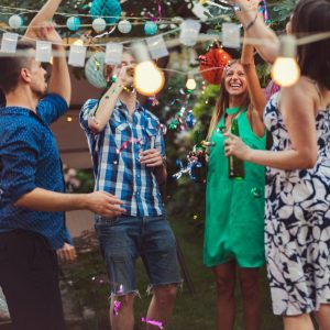 Convives se détendant et profitant du jardin lors de la garden party, entourés de verdure et de fleurs colorées