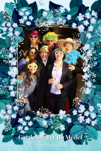 Groupe d'invités déguisés posant devant le cadre fleuri du photobooth